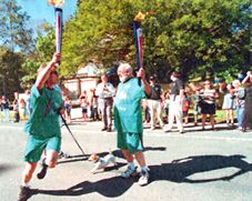 Tom Keneally hands the Paralympic flame on to Yahoo Serious. Photo: Steven Siewert